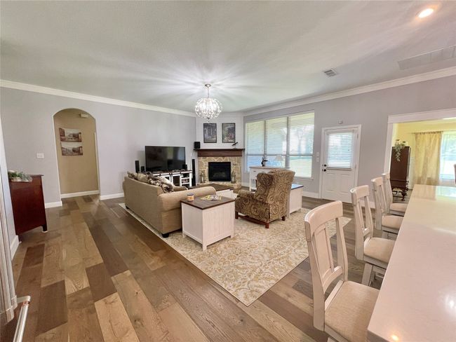 Living area featuring arched walkways, baseboards, wood finished floors, ornamental molding, and healthy amount of natural light | Image 16