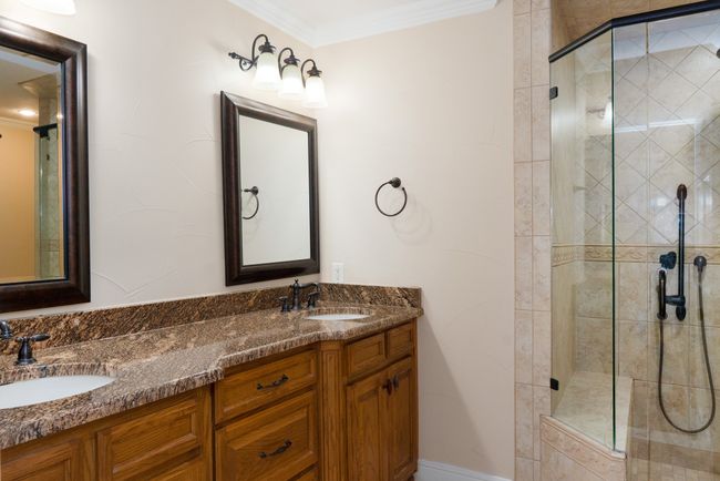 Full bath featuring a shower stall, double vanity, and ornamental molding | Image 31