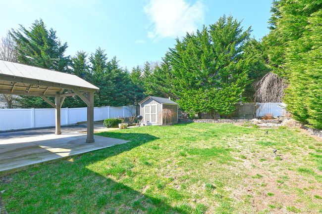 View of yard featuring a patio area, a gazebo, an outbuilding, a storage shed, and a fenced backyard | Image 16