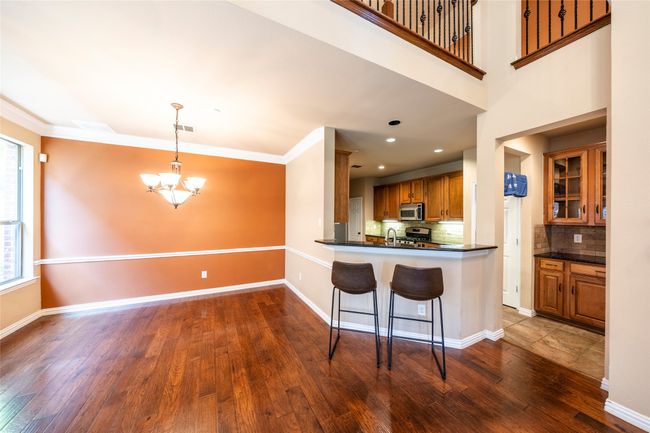Kitchen featuring brown cabinets, a chandelier, dark countertops, decorative backsplash, and crown molding | Image 11