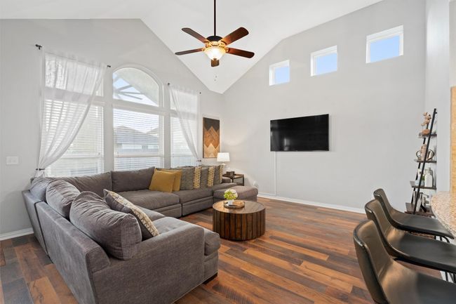 Living area with a ceiling fan, high vaulted ceiling, and wood finished floors | Image 12