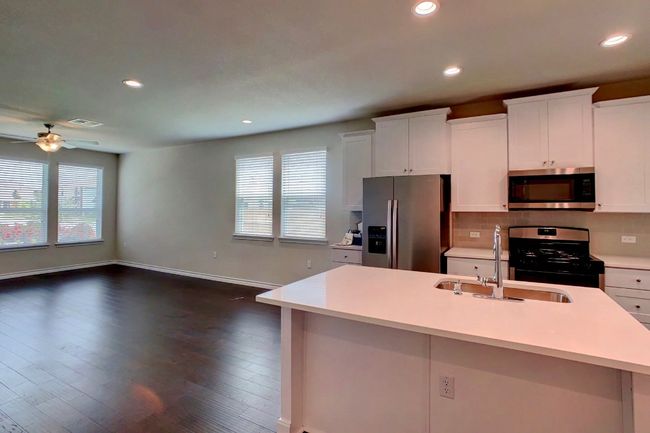 Kitchen featuring light countertops, ceiling fan, appliances with stainless steel finishes, a sink, and a healthy amount of sunlight | Image 9