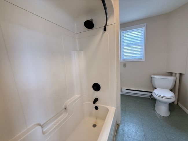 Bathroom featuring tile patterned floors, toilet, washtub / shower combination, and baseboard heating | Image 5