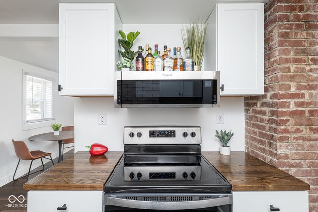 kitchen with appliances with stainless steel finishes, wood finished floors, white cabinetry, and wooden counters | Image 12