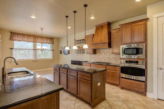Kitchen featuring a center island, backsplash, a sink, appliances with stainless steel finishes, and custom exhaust hood | Image 11