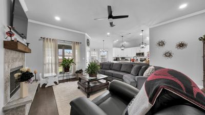 Living room featuring ornamental molding, ceiling fan with notable chandelier, and hardwood / wood-style floors | Image 3