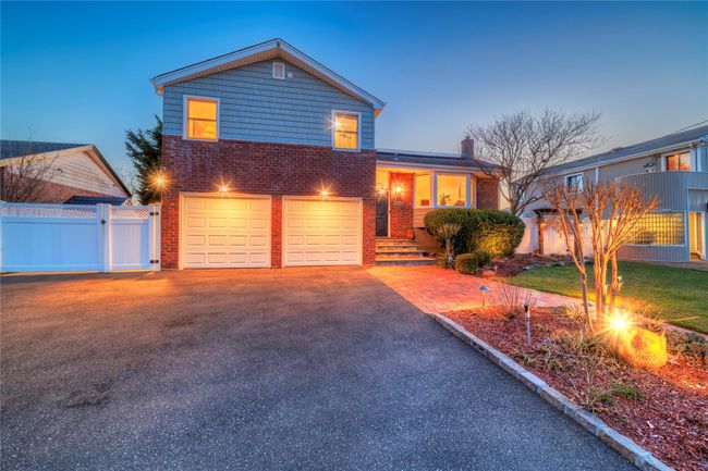 Tri-level home featuring aphalt driveway, fence, a gate, a garage, and brick siding | Image 44