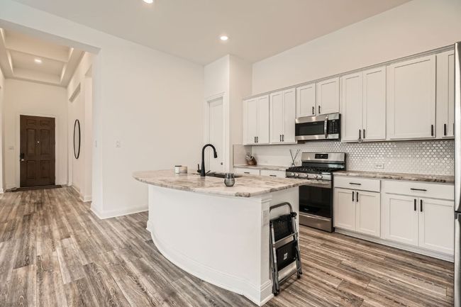 Kitchen with appliances with stainless steel finishes, decorative backsplash, an island with sink, light wood-style floors, and recessed lighting | Image 8