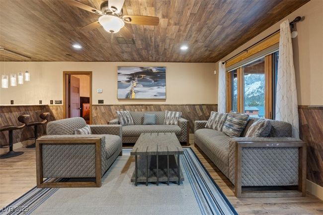 Living area featuring visible vents, wooden ceiling, wainscoting, and wooden walls | Image 40