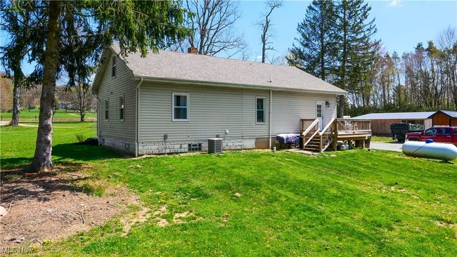 Back of house with a wooden deck, a yard, a shingled roof, and a chimney | Image 28