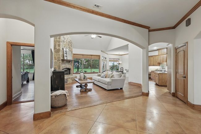 Living area with ornamental molding, light tile patterned flooring, ceiling fan, arched walkways, and a fireplace | Image 8