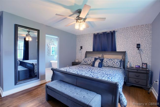 Bedroom with dark hardwood / wood-style flooring, ceiling fan, and connected bathroom | Image 42
