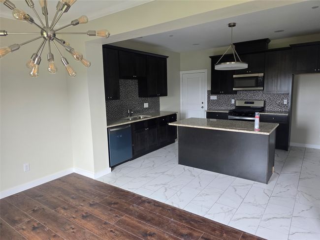 Kitchen featuring stainless steel appliances, dark cabinetry, and baseboards | Image 6