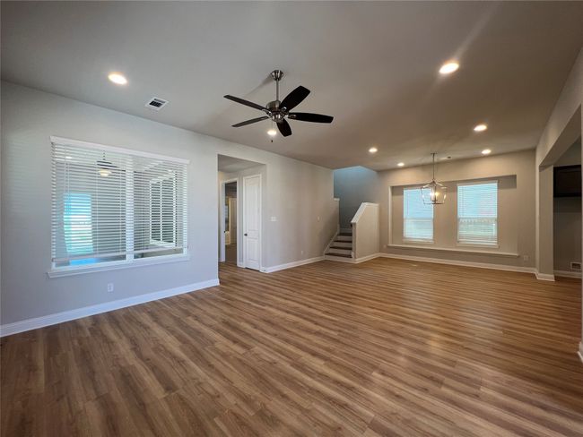 Unfurnished living room featuring stairway, wood finished floors, baseboards, recessed lighting, and a ceiling fan | Image 4
