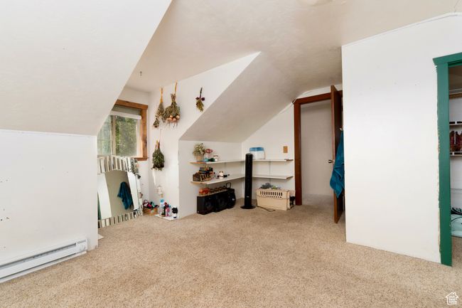 Additional living space with a baseboard radiator, carpet floors, and lofted ceiling | Image 25