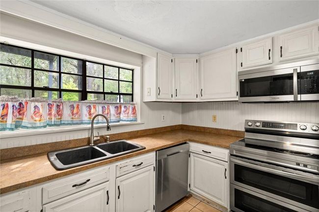 Kitchen with white cabinets and stainless steel appliances. | Image 5