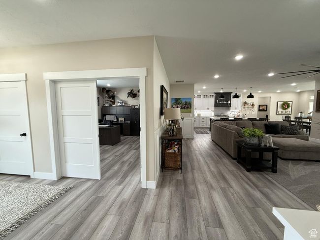 Living room with visible vents, baseboards, recessed lighting, a ceiling fan, and light wood-style floors | Image 8