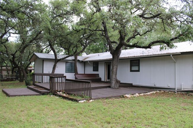 Rear view of property with a jacuzzi, a deck, metal roof, and a lawn | Image 24