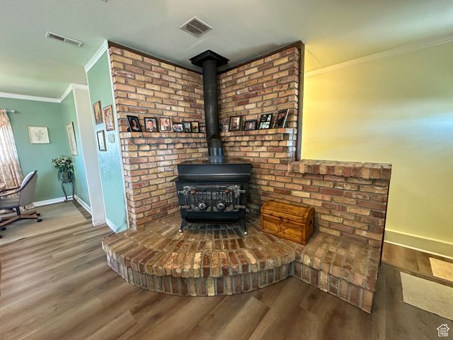 Detailed view of crown molding, wood finished floors, and a wood stove | Image 13