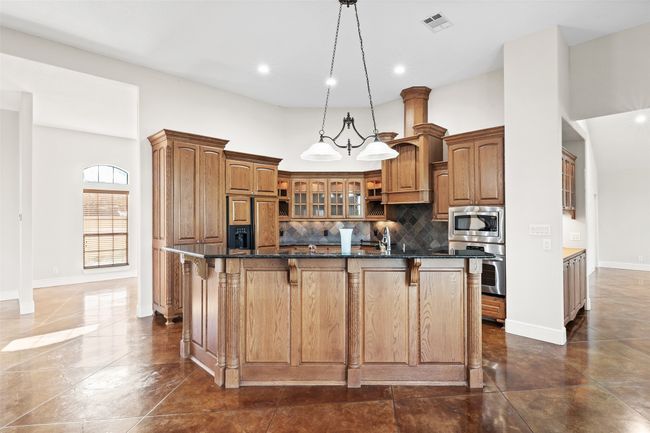 Kitchen featuring built in appliances, a kitchen bar, glass insert cabinets, backsplash, and recessed lighting | Image 6