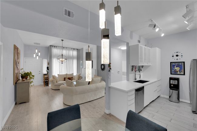Kitchen with stainless steel appliances, light countertops, white cabinetry, and light wood finished floors | Image 11