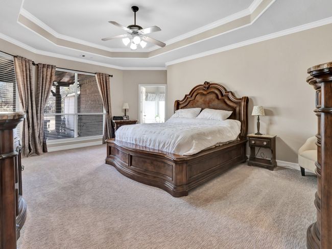 Carpeted bedroom featuring ceiling fan, baseboards, ornamental molding, and a raised ceiling | Image 23