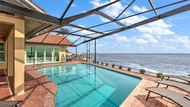 Outdoor pool with a water view, a patio area, and glass enclosure | Image 6