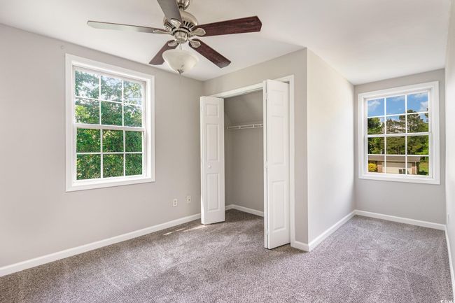 Unfurnished bedroom featuring baseboards, a closet, multiple windows, and carpet flooring | Image 17