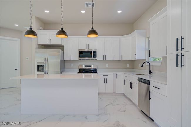 Kitchen with visible vents, marble finish floor, appliances with stainless steel finishes, a sink, and a center island | Image 6