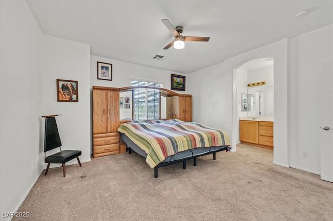 Bedroom featuring light colored carpet, arched walkways, a ceiling fan, and connected bathroom | Image 15