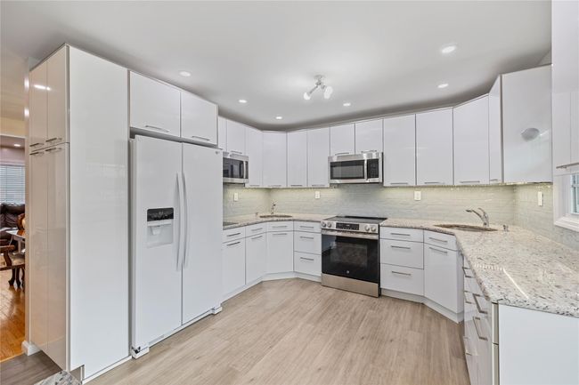 Kitchen featuring stainless steel appliances, a sink, light wood-style floors, and tasteful backsplash | Image 19