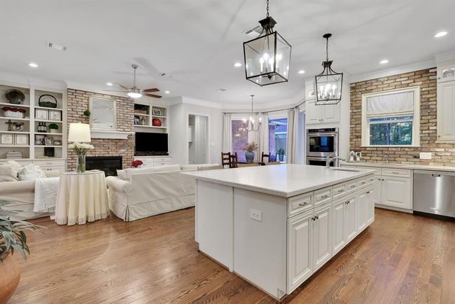 The rustic brick backsplash adds warmth and texture, complementing the elegant countertops and floor-to-ceiling white cabinetry, which ensures abundant storage. | Image 13
