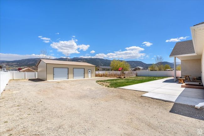 View of yard featuring a fenced backyard, a patio area, an outbuilding, a mountain view, and a garage | Image 60