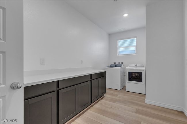 Laundry area with independent washer and dryer, light wood finished floors, cabinet space, baseboards, and recessed lighting | Image 28