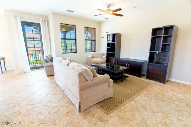 Living area featuring light tile patterned floors, a ceiling fan, visible vents, and a healthy amount of sunlight | Image 7