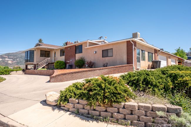 View of front of house with brick siding, a garage, driveway, stairway, and a chimney | Image 52