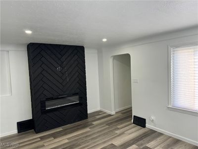 Spare room with hardwood / wood-style flooring, a fireplace, and a textured ceiling | Image 3