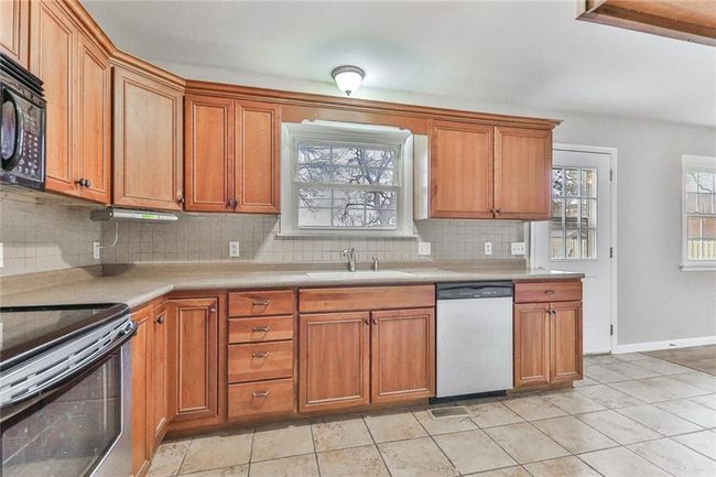 Kitchen featuring backsplash, sink, light tile patterned flooring, and appliances with stainless steel finishes | Image 5