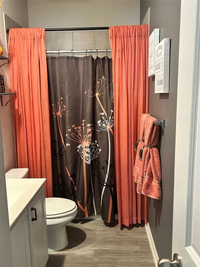 Bathroom featuring toilet, vanity, wood finished floors, and curtained shower | Image 6