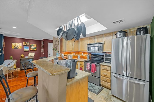 Kitchen featuring light countertops, light brown cabinetry, visible vents, a peninsula, and appliances with stainless steel finishes | Image 9