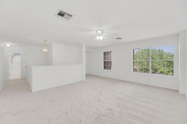 Unfurnished room featuring attic access, light carpet, visible vents, and ceiling fan | Image 24