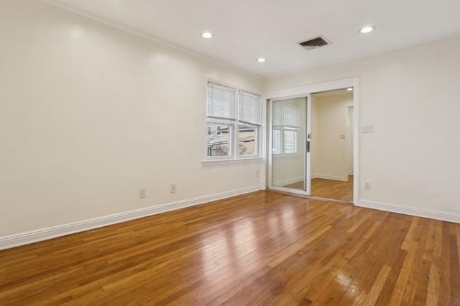 Unfurnished bedroom with baseboards, crown molding, visible vents, and light wood-style flooring | Image 15