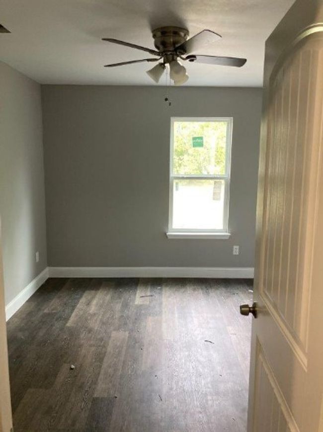 Unfurnished room featuring dark wood-style flooring, baseboards, and ceiling fan | Image 7