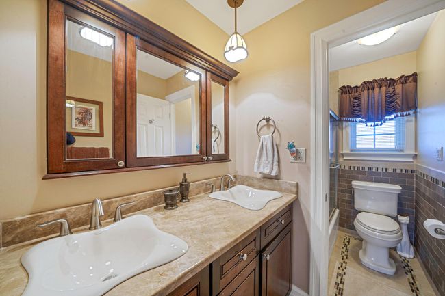 Bathroom featuring toilet, a sink, tile patterned floors, and tile walls | Image 23