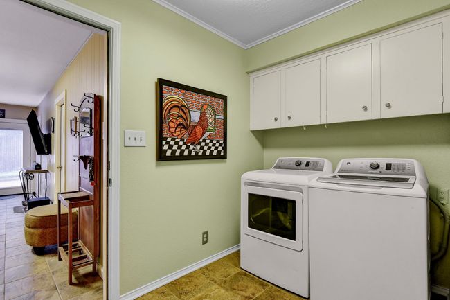 Laundry area featuring cabinet space, washer and clothes dryer, crown molding, and baseboards | Image 18