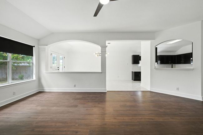 Living room with lofted ceiling, a ceiling fan, a tile fireplace, wood finished floors, and arched walkways | Image 10
