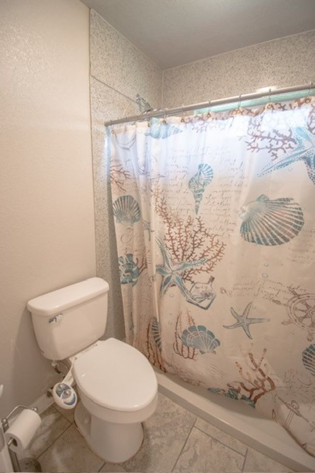 Full bathroom with toilet, a shower with curtain, and tile patterned floors | Image 13