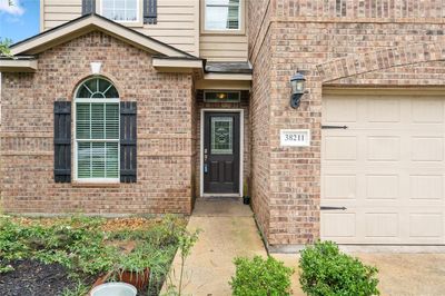 This is a two-story brick home with contrasting trim, featuring a prominent front window with shutters and a welcoming front door. | Image 3