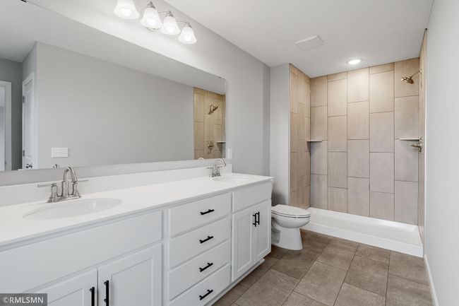 (Photo of previously finished home) The luxurious owner's suite features a spacious, elegant bathroom with dual vanities, sleek white cabinetry, and a modern countertop. | Image 13