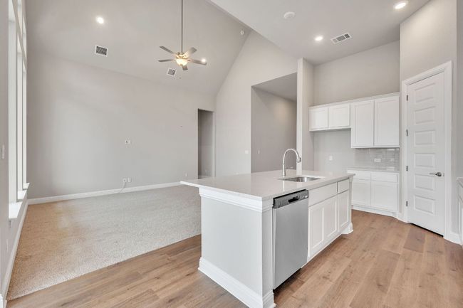 Kitchen featuring a sink, white cabinetry, open floor plan, dishwasher, and an island with sink | Image 8